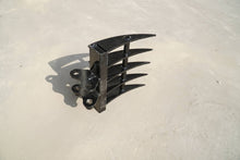Rippa Australia black Excavator Rake attachment with curved tines on concrete surface